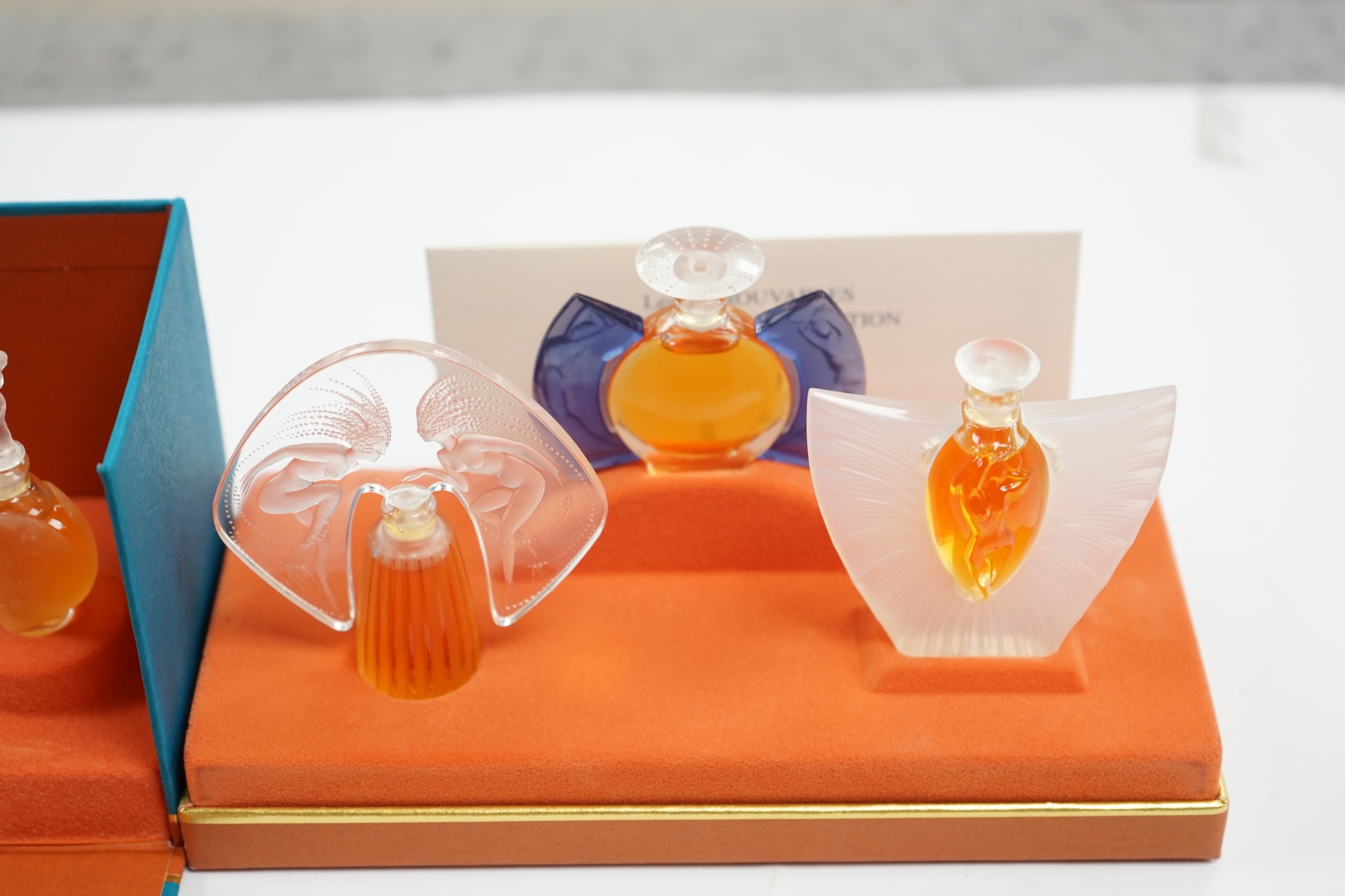 Two Lalique sets of three miniature perfume bottles. 'Les flacons miniatures' 1996-1997 and 1998-2000, boxed and sealed, tallest 7cm high. Condition - good